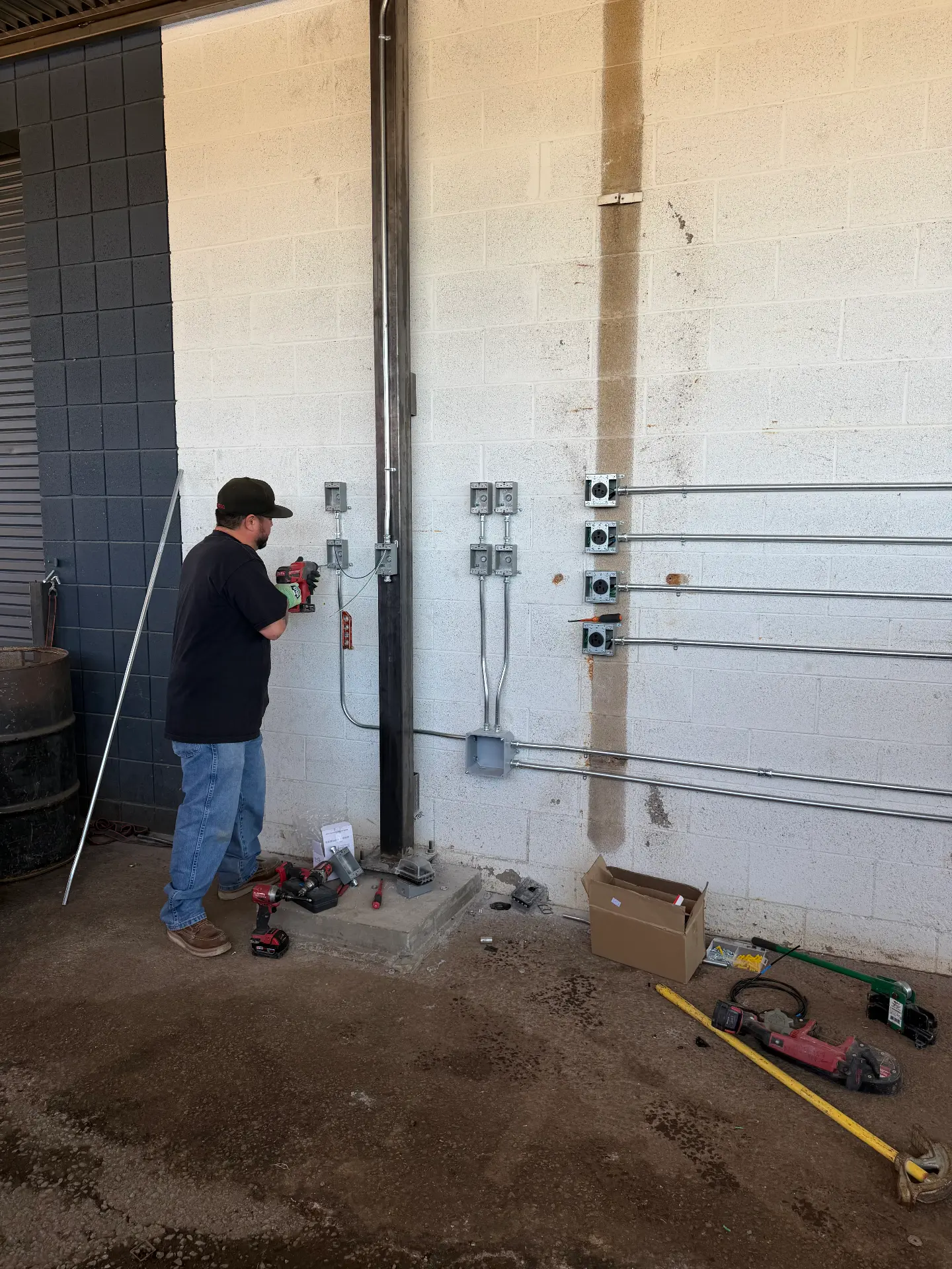 Electrician installing conduit runs and outlet boxes in a commercial warehouse