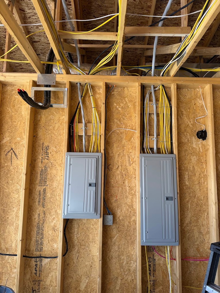 Two newly installed load centers in a framed garage wall
