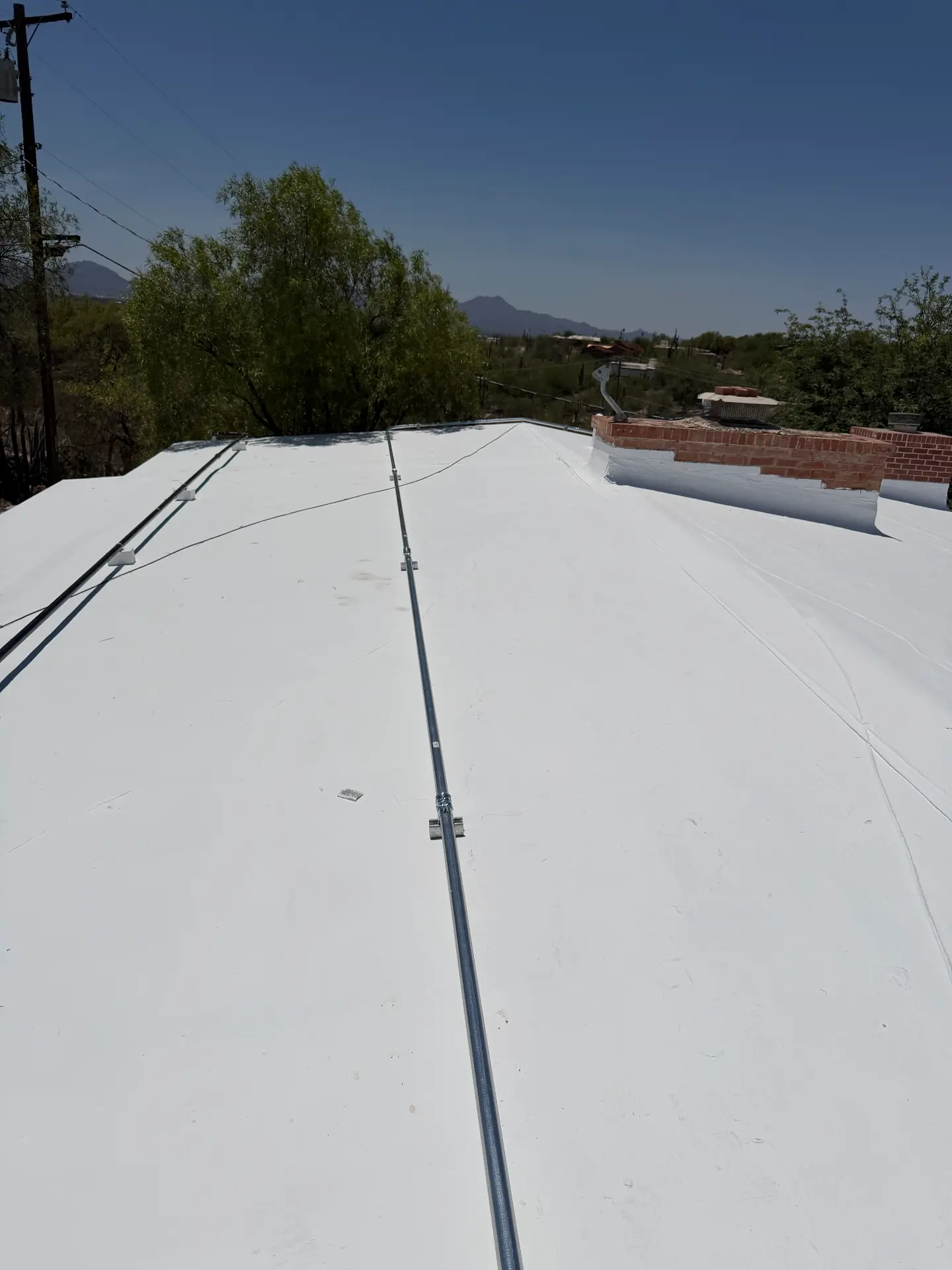 Rooftop conduit run installed across a coated flat roof